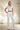 Wisteria Lane long bootcut white denim jumpsuit displayed on a hanger with front pockets and wide-leg style.