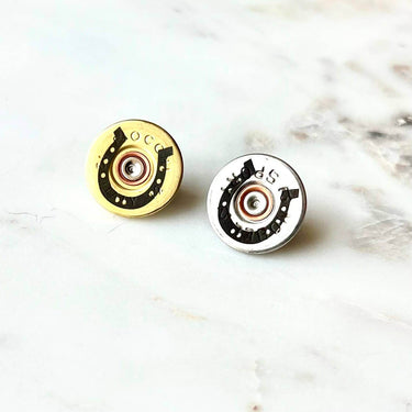 Bronze shotgun shell and horseshoe lapel pin by Brand Dandee, featuring detailed metal craftsmanship and classic western design.