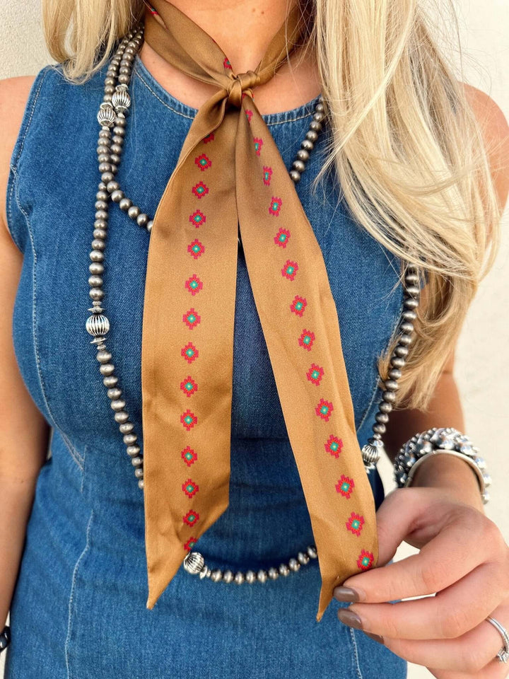 Tan silk Twilly scarf with vibrant purple, teal, orange, and yellow accents from West & Co.
