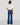 Person wearing blue jeans and a white top on a plain background