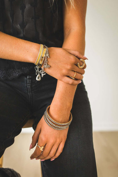 West & Co. 18K plated dotted jewelry bangle set featuring multiple slim, textured bangles for stylish accessory wear.