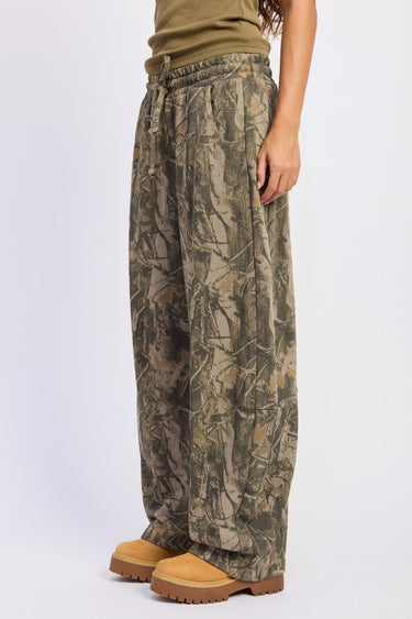 Emory Park Woodland Camo Barrel Leg Drawstring Pants showing green and brown camouflage fabric with drawstring waist and relaxed fit