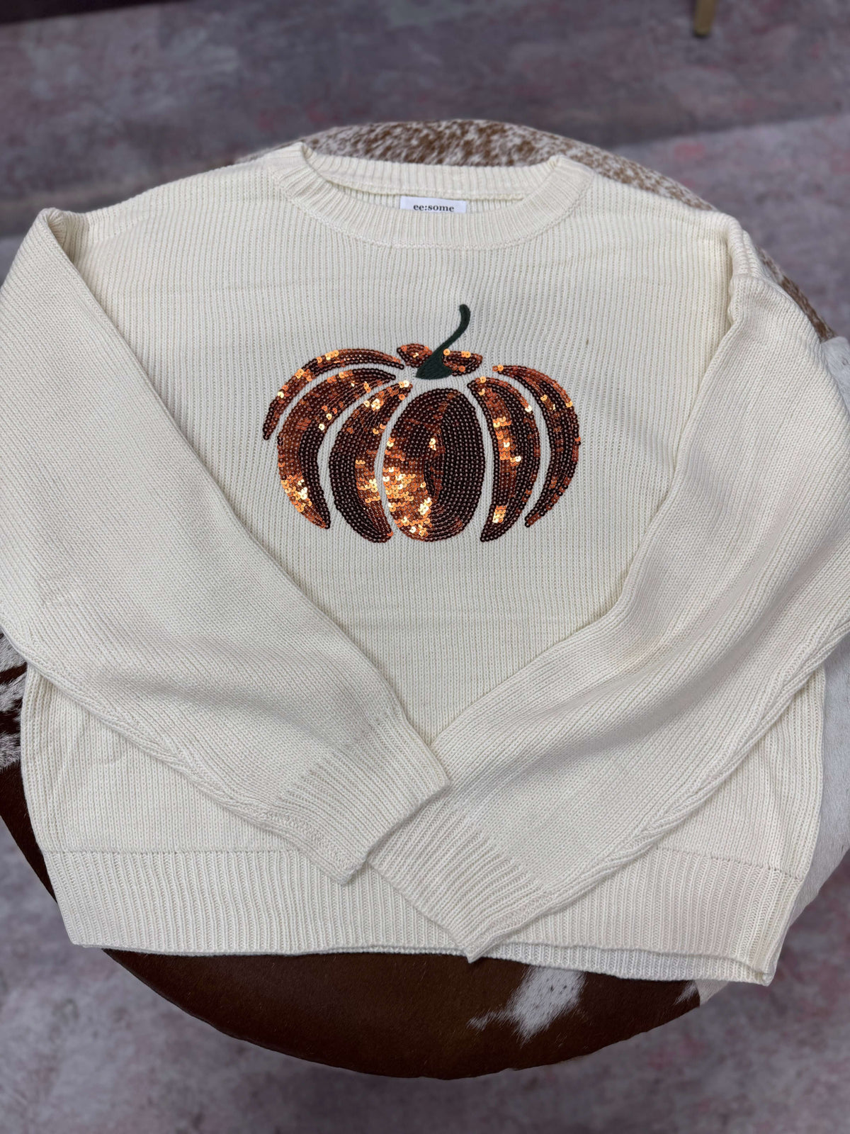Pink pumpkin glitter sweater from ee:some featuring a cozy knit design with shimmering embellishments.