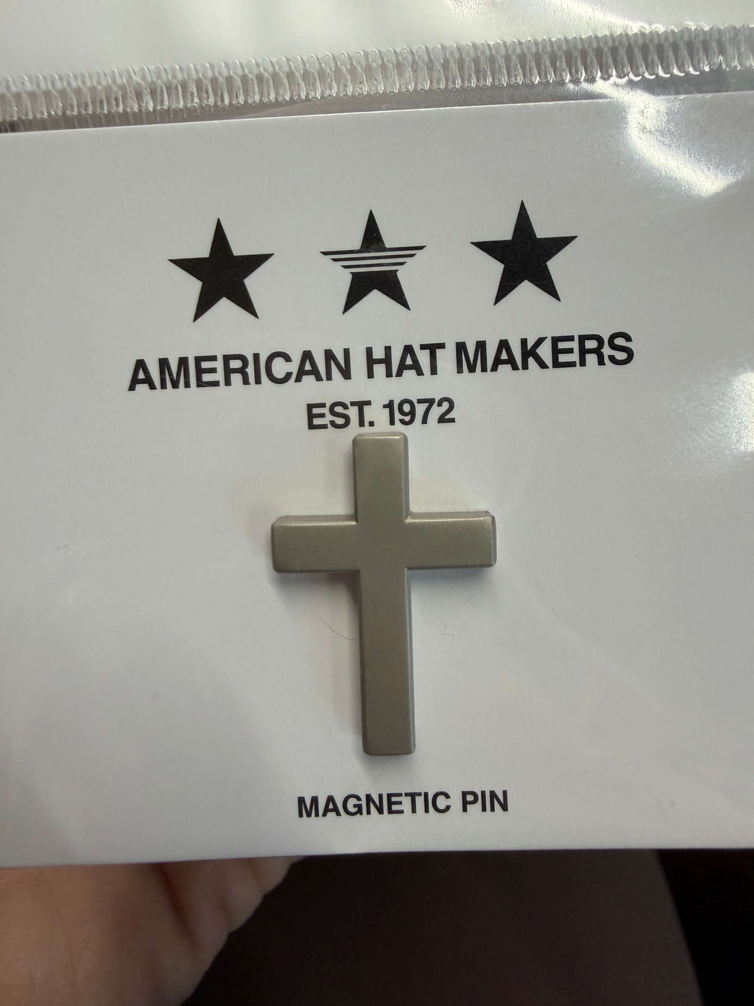 Silver cross magnetic pin on a 'American Hat Makers' branded card