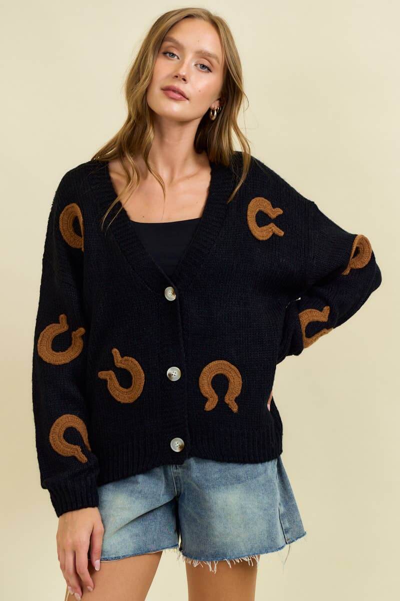 Doe and Rae horseshoe patch cardigan, a cozy sweater with distinctive horseshoe patch detail and ribbed knit texture.