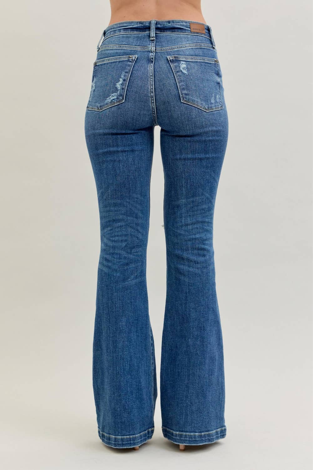 Distressed Judy Blue midrise button fly flare jeans with a trendy fit, shown in a natural pose highlighting the distressed details.