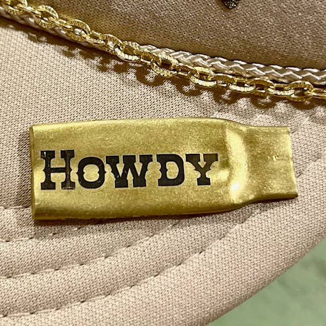 Smashed bullet casing lapel pin with "HOWDY" text, a metal accessory by Brand Dandee, suitable for clothing or bags.
