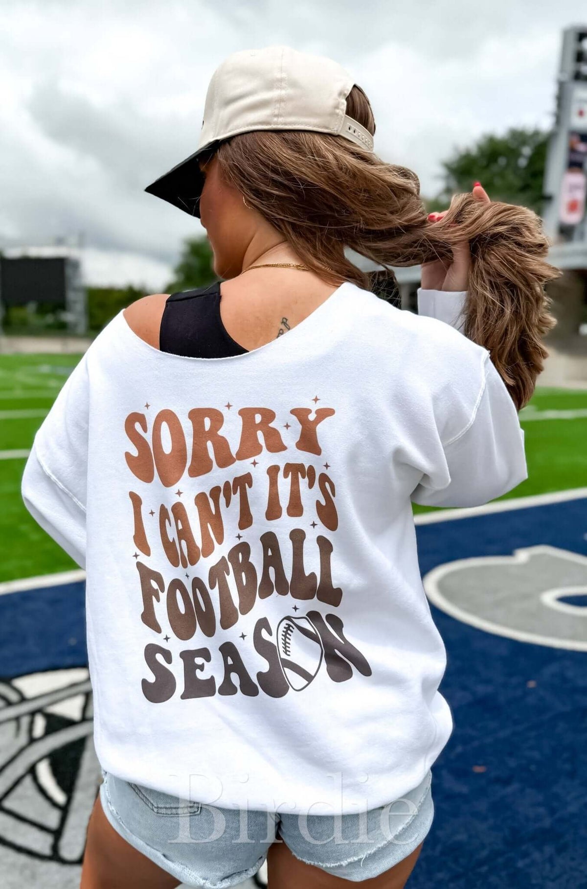 Birdie white graphic off-shoulder crew sweatshirt with "Sorry Can't Football Season" design, perfect for casual wear.